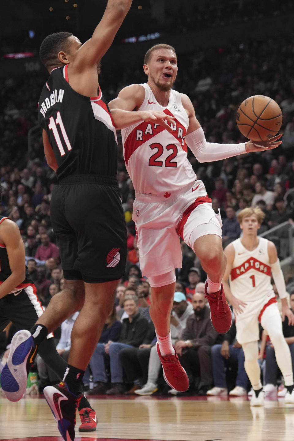 Toronto Raptors guard Malachi Flynn (22) heads toward the basket as Portland Trail Blazers guard Malcolm Brogdon (11) defends during first-half NBA basketball game action in Toronto, Monday, Oct. 30, 2023. (Nathan Denette/The Canadian Press via AP)