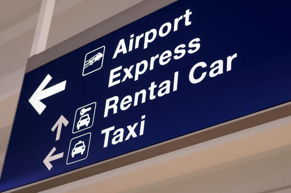An airport sign with direction arrows for rental cars and taxis.