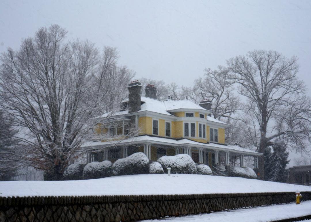 A yellow two story home in the snow.