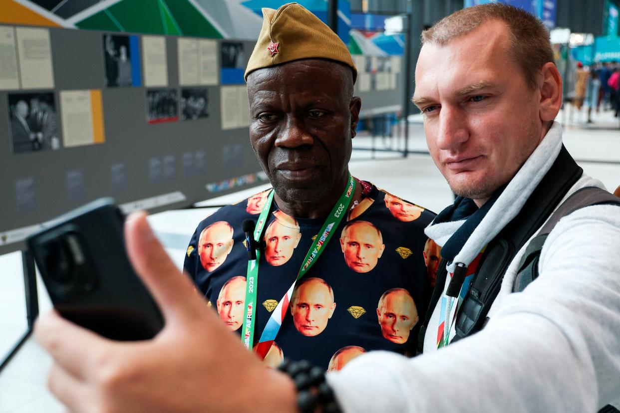 Guinean embassy staff member Lama Jacques Sevoba, left, wearing a T-shirt with images of Russian President Vladimir Putin poses for a photo (AP)