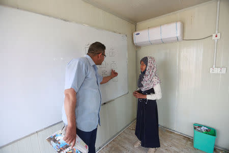 A teacher talks with a girl of Iraqi Kawliya group (known as Iraqi gypsies) at a school at al-Zuhoor village near the southern city of Diwaniya, Iraq April 16, 2018. Picture taken April 16, 2018. REUTERS/Alaa Al-Marjani