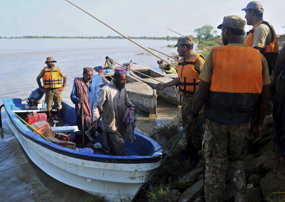 Pakistani army soldiers evacuate villagers from a flooded areas of Dadu, a district in Pakistan's southern Sindh province, Sunday, Aug. 9, 2020. Three days of heavy monsoon rains triggering flash floods killed at least dozens people in various parts of Pakistan, as troops with boats rushed to a flood-affected district in the country's southern Sindh province Sunday to evacuate people to safer places. (AP Photo/Pervez Masih)