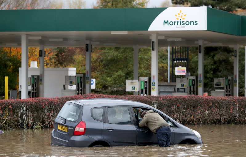 A man looks inside a car stranded in a flooded road in central Rotherham, near Sheffield