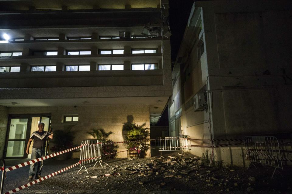 A man stands outside a Jewish religious school in Sderot, Israel, after it was hit by a rocket fired from the Gaza Strip, Thursday, June 13, 2019. (AP Photo/Tsafrir Abayov)