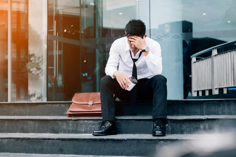 A man sits on a staircase with his head down.