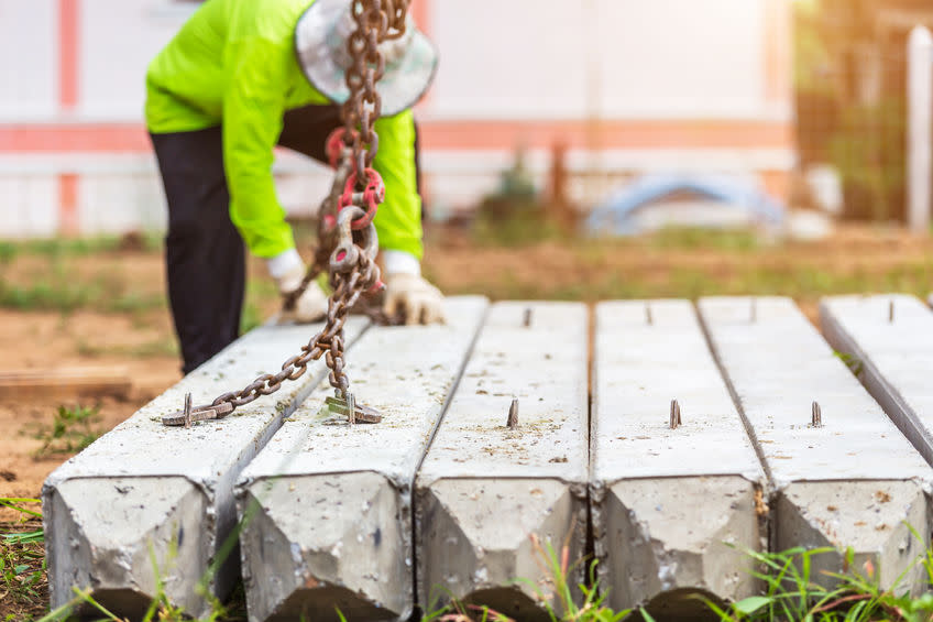 Construction worker unloading concrete stake from truck