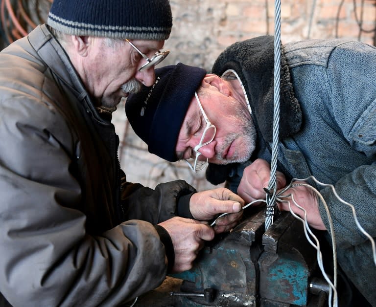 Ship captain Waldemar Rzeznicki (R) and Michal Jedynak work on steel ropes for a steel schooner named 'Father Boguslaw' under construction at the courtyard of a homeless shelter run by Catholic Fathers, in Warsaw