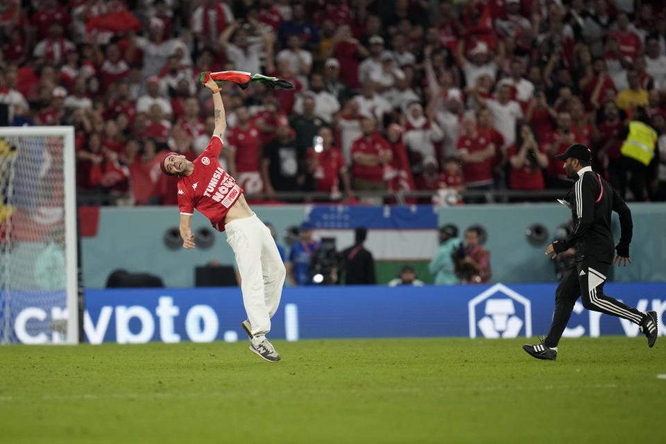 A Tunisian soccer fan invades the pitch during the World Cup group D soccer match between Tunisia and France at the Education City Stadium in Al Rayyan , Qatar, Wednesday, Nov. 30, 2022. (AP Photo/Christophe Ena)