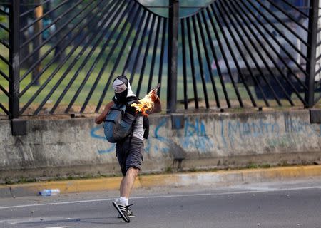 A demonstrator throws a petrol bomb while clashing with riot security forces during a rally against Venezuela's President Nicolas Maduro's Government outside of an Air Force base in Caracas, Venezuela, June 23, 2017. REUTERS/Ivan Alvarado