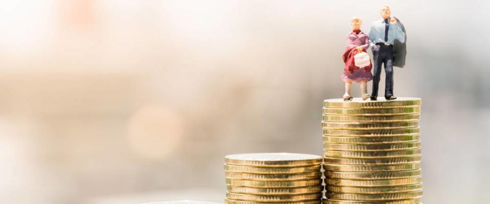 Concepts of retirement planning and finanacial. Miniature people: Old couple figure standing on top of coin stack.