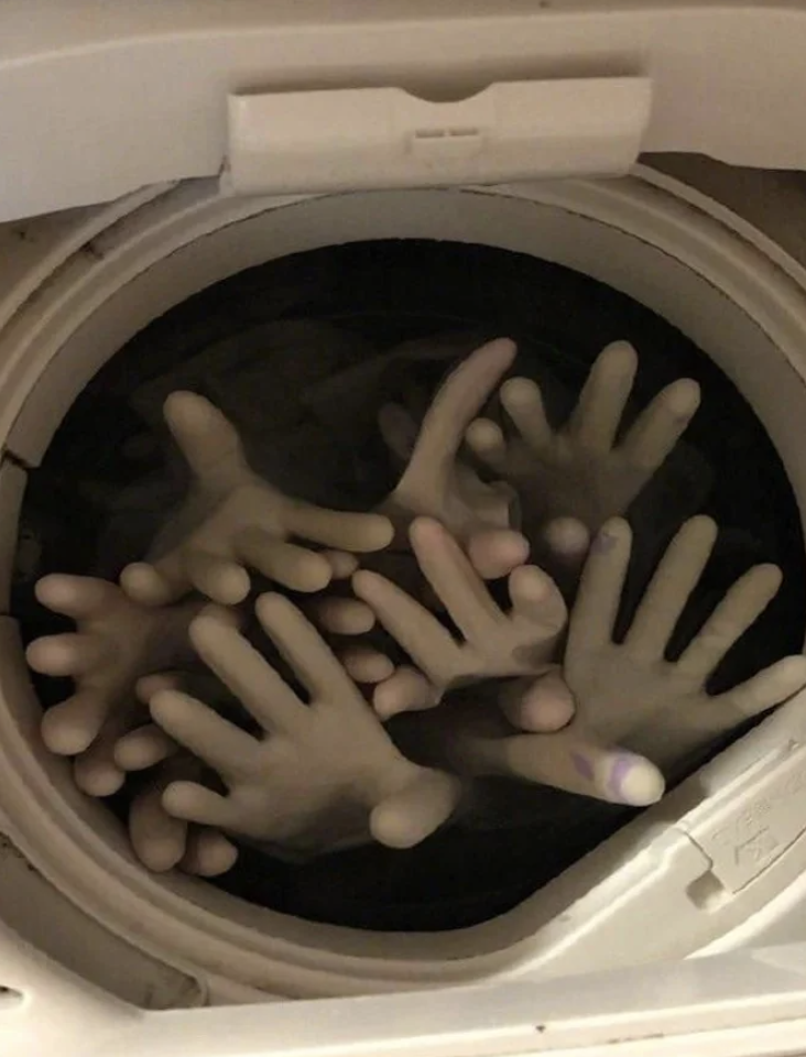 A washing machine filled with multiple rubber gloves placed in a way that makes it look as if several hands are reaching out