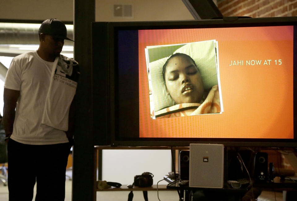 In this Dec. 23, 2015, photo, Jahi McMath is shown on a video screen next to her uncle Timothy Whisenton, at a news conference in San Francisco. (AP Photo/Jeff Chiu, file)