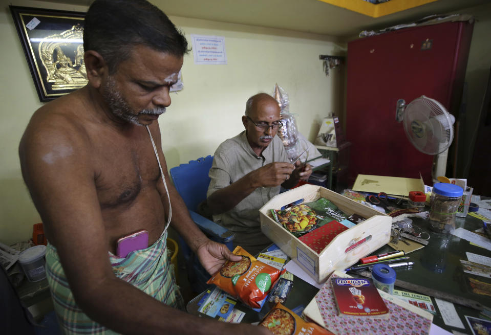 A Hindu priest, left, and a temple official open a box full of packaged food and sweets sent by a non-government organization to be distributed among villagers ahead of the inauguration of U.S. Vice President-elect Kamala Harris, in Thulasendrapuram, the hometown of Harris' maternal grandfather, south of Chennai, Tamil Nadu state, India, Tuesday, Jan. 19, 2021. The inauguration of President-elect Joe Biden and Vice President-elect Kamala Harris is scheduled be held Wednesday. (AP Photo/Aijaz Rahi)