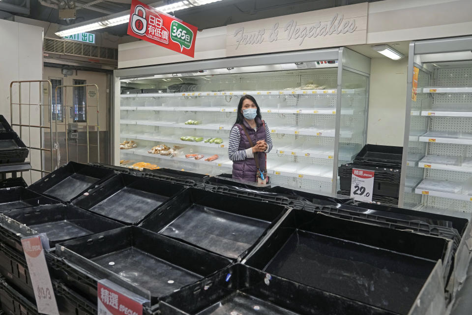 FILE - A woman walks past empty shelves and freezers as residents concerned with possible shortages, stock up on food at a supermarket in Hong Kong on March 4, 2022. The fast-spreading omicron variant is overwhelming Hong Kong, prompting mass testing, quarantines, supermarket panic-buying and a shortage of hospital beds. Even the morgues are overflowing, forcing authorities to store bodies in refrigerated shipping containers. (AP Photo/Kin Cheung, File)