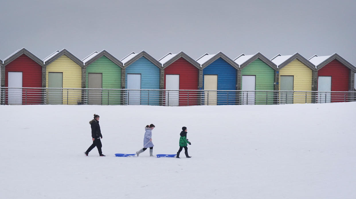 People walk through the snow beside the beach huts at Blyth in Northumberland, as temperatures are tipped to plunge to as low as minus 11C in parts of the UK over the weekend. Picture date: Sunday December 3, 2023. (Photo by Owen Humphreys/PA Images via Getty Images)