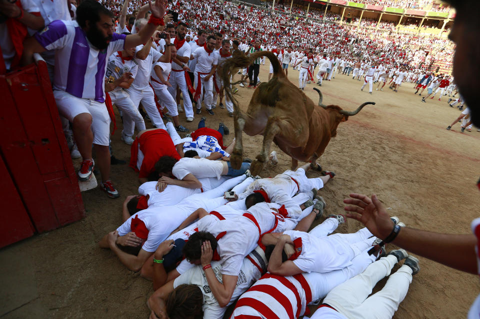 <p>Revellers protect themselves as a calf jumps over them in the bullring after the 4th day of the running of the bulls at the San Fermin Festival in Pamplona, northern Spain, July 10, 2018. (Photo: Alvaro Barrientos/AP) </p>