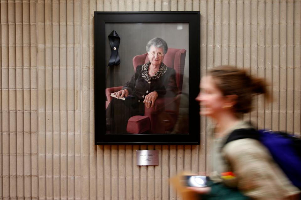 A student walks past a portrait of Claire T. Carney in her namesake library at UMass Dartmouth.