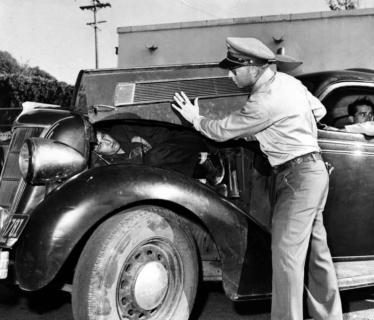 A U.S. Border Patrol officer shows how he found an undocumented Mexican immigrant under the hood of a car along the U.S.-Mexican border in March 1954. <a href="https://mapi.associatedpress.com/v2/items/4dfcc46d4de4da11af9f0014c2589dfb/preview/AP540315014.jpg?wm=api&tag=app_id=1,user_id=904438,org_id=101781" rel="nofollow noopener" target="_blank" data-ylk="slk:Associated Press;elm:context_link;itc:0;sec:content-canvas" class="link ">Associated Press</a>