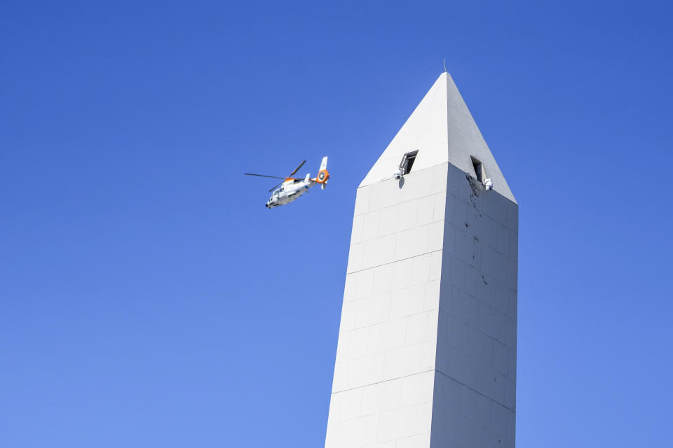 A helicopter flies over the Obelisk where people gathered in hopes of seeing the Argentine national soccer team that won the World Cup title in Buenos Aires, Argentina, Tuesday, Dec. 20, 2022. So many people swarmed highways surrounding the capital that the players ended up having to abandon the bus and get on helicopters, and what was set to become a parade through the streets became an aerial parade. (AP Photo/Matilde Campodonico)