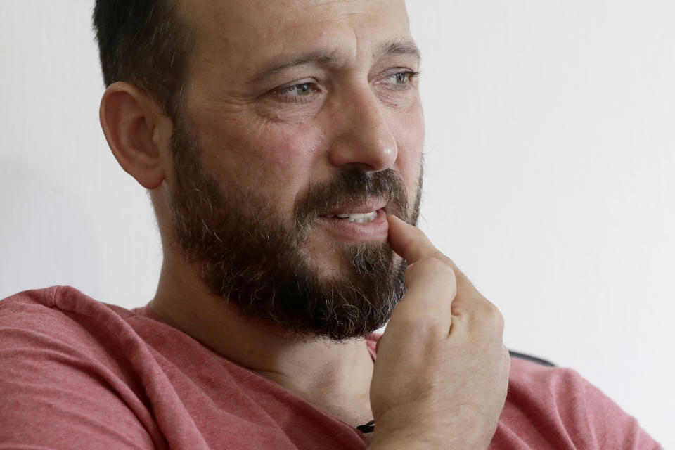 In this Tuesday, Feb. 25, 2020, photo, Al Noor mosque shooting survivor Temel Atacocugu gestures to where the first bullet hit him during an interview at his home in Christchurch, New Zealand. When the gunman walked into the mosque, Atacocugu was kneeling for Friday prayers. He looked up into the man's face, thinking he was a police officer because of his paramilitary outfit. Time slowed. Temel saw a puff of smoke come from the raised gun, felt a bullet smash into his teeth, and thought: "Oh, my God, I'm dying." (AP Photo/Mark Baker)