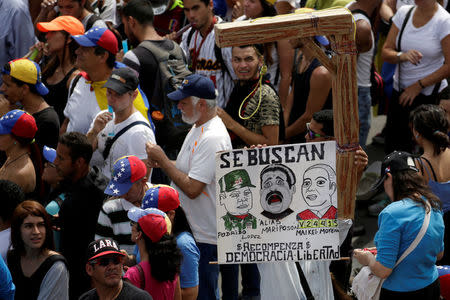 Opposition supporters carry a placard depicting (L-R) Venezuela's Defense Minister Vladimir Padrino Lopez, Venezuela's President Nicolas Maduro and Venezuela's Supreme Court President Maikel Moreno that reads "Wanted" during a rally in Caracas, Venezuela April 24, 2017. REUTERS/Marco Bello