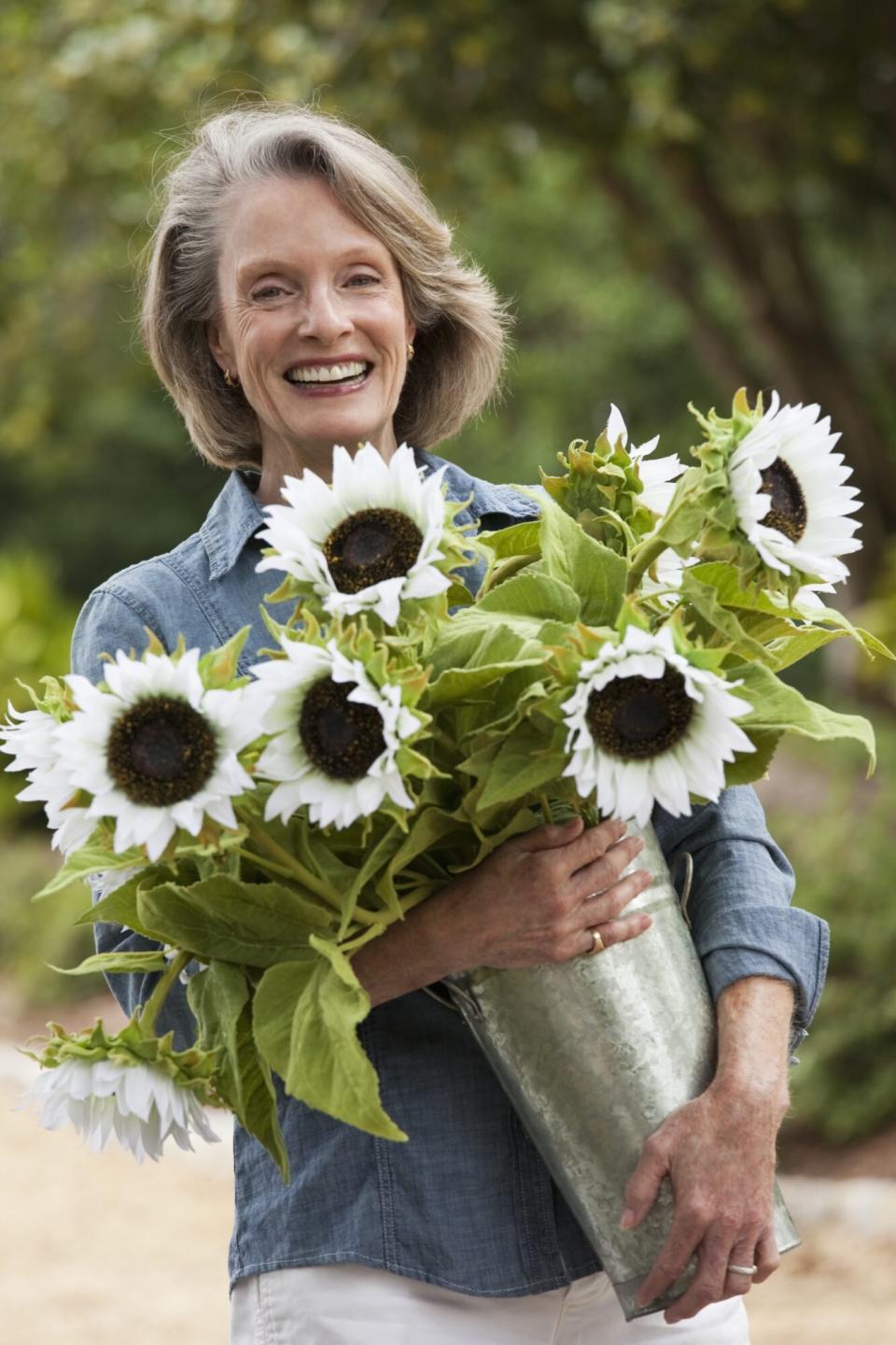 Caucasian woman carrying vase of sunflowers