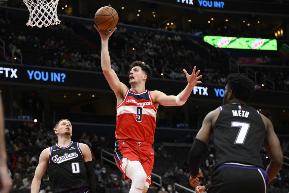 Washington Wizards forward Deni Avdija (9) goes to the basket against Sacramento Kings guard Donte DiVincenzo (0) and forward Chimezie Metu (7) during the first half of an NBA basketball game Saturday, Feb. 12, 2022, in Washington. (AP Photo/Nick Wass)