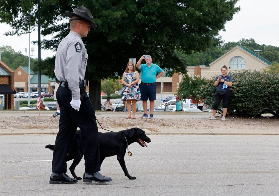 A Wake County deputy walks with Sasha, the K9 partner of slain Wake County Deputy Ned Byrd, as the N.C. State Highway Patrols Caisson Unit carries Byrds casket down Glenwood Avenue on Friday, Aug. 19, 2022, in Raleigh, N.C. Byrd was found dead with multiple gunshot wounds early Friday morning, Aug. 12 in southeastern Wake County.