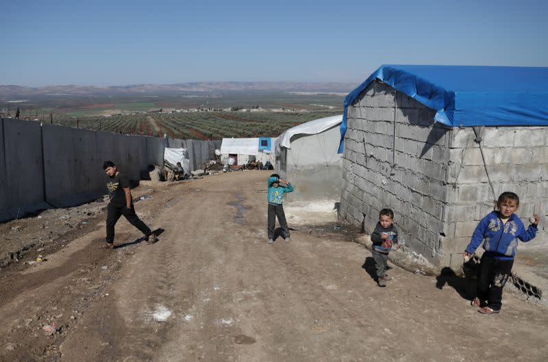 FILE PHOTO: Internally displaced Syrian children walk near the wall in Atmah IDP camp, located near the border with Turkey