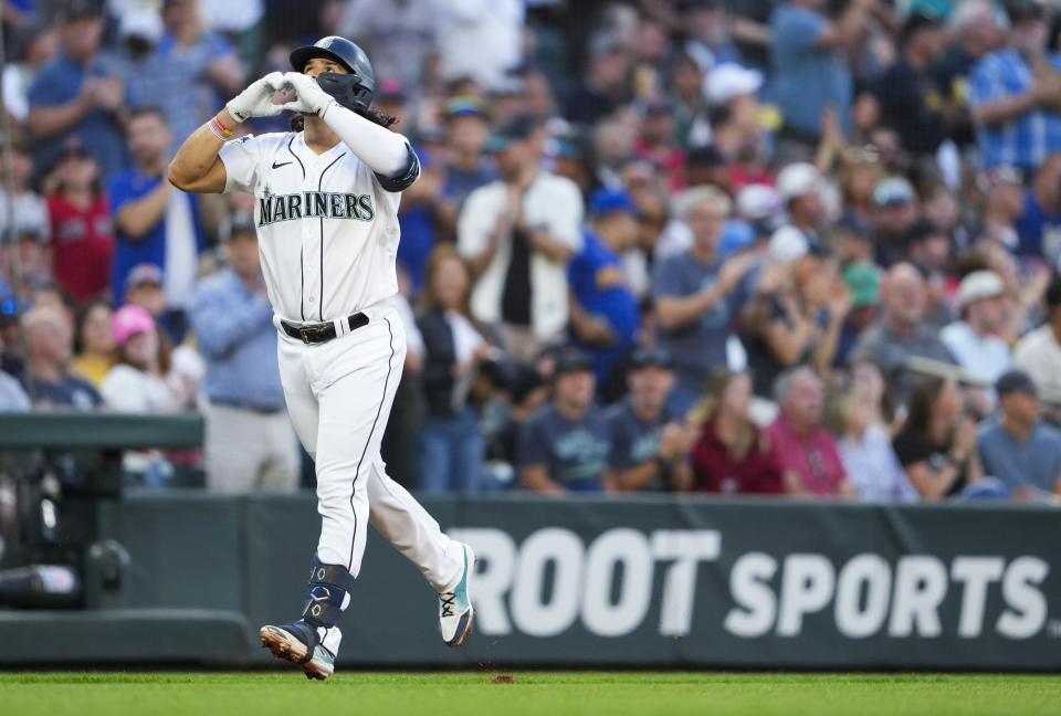 Seattle Mariners' Eugenio Suarez makes a heart as he rounds the bases after hitting a two-run home run during the fifth inning of a baseball game against the Boston Red Sox, Tuesday, Aug. 1, 2023, in Seattle. (AP Photo/Lindsey Wasson)