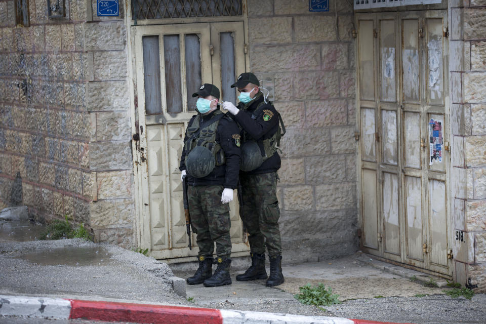 Members of Palestinian security forces wear masks as a preventive measure against the coronavirus as they stand guard outside a hotel which staff tested positive in Bethlehem, West Bank, Friday, March 6, 2020. Foreign tourists say they are being denied entry to the biblical West Bank city of Bethlehem a day after Israeli and Palestinian authorities took measures to prevent the spread of the new coronavirus. (AP Photo/Majdi Mohammed)