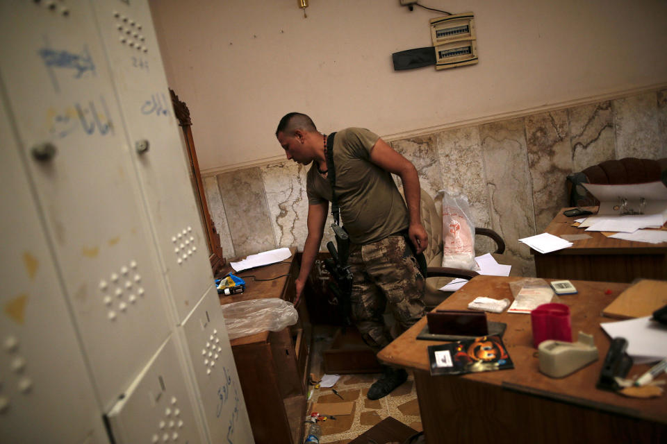 <p>A member of the Iraqi Army’s 9th Armoured Division searches through a desk inside a compound used as a prison by Islamic State militants in the 17 Tamuz (July 17) district, in western Mosul, Iraq, June 6, 2017. (Alkis Konstantinidis/Reuters) </p>