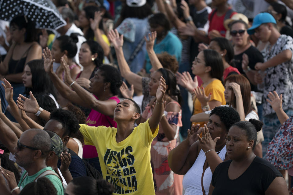 Christians raise their hands in praise during an International Grace of God Church event led by televangelist R.R. Soares, with President Jair Bolsonaro in attendance, at Botafogo beach in Rio de Janeiro, Brazil, Saturday, Feb. 15, 2020. Tens of thousands of people gathered to celebrated the 40th anniversary of the evangelical church. (AP Photo/Leo Correa)