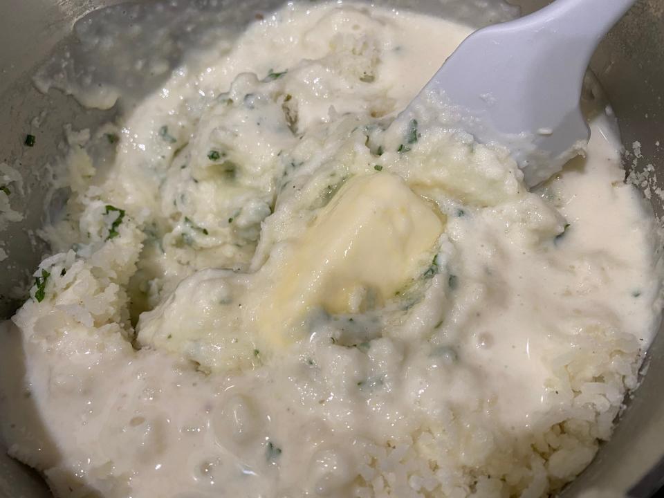 mixing butter, mashed potatoes, and bechamel sauce in a big metal pot