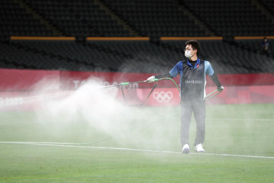 <p>An official sprays disinfectant onto the pitch in an attempt to halt the spread of the Covid-19 coronavirus ahead of the Tokyo 2020 Olympic Games men's group C first round football match between Argentina and Australia at the Sapporo Dome in Sapporo on July 22, 2021. (Photo by ASANO IKKO / AFP) </p> 