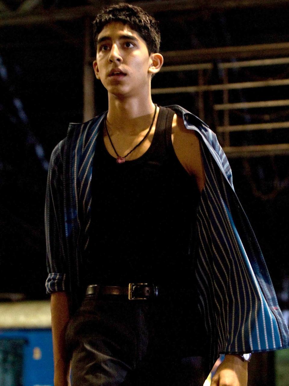 Dev in an open striped shirt and undershirt and bowl-cut hair