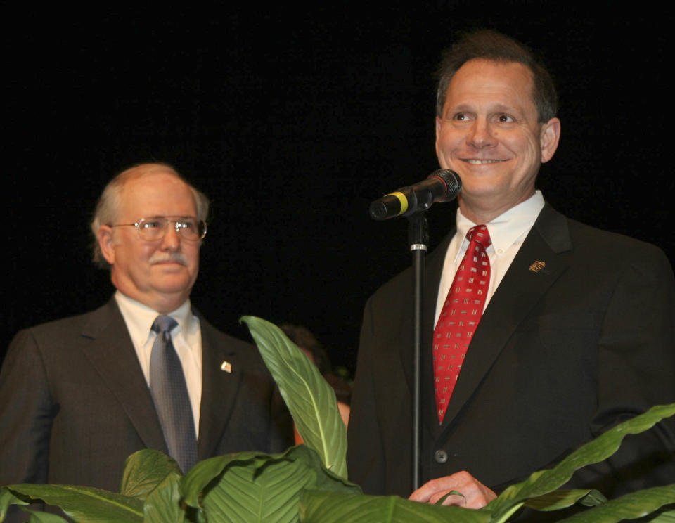 FILE - Tom Parker, left, listens as former Alabama Supreme Court Chief Justice Roy Moore, right, addresses the crowd at the Davis Theater in Montgomery, Ala. on Jan. 14, 2005, before swearing in Parker as an associate justice of the court. When the Alabama Supreme Court ruled that frozen embryos are children, its Chief Justice Tom Parker made explicit use of Christian theology to justify the court's decision in his concurrence, where his language echoed the broader anti-abortion movement. Parker is no stranger to church-state debates. He served as former Chief Justice Moore's spokesperson during fights over a Ten Commandments monument that Moore erected in the Alabama Supreme Court building. (AP Photo/Jay Sailors, File)