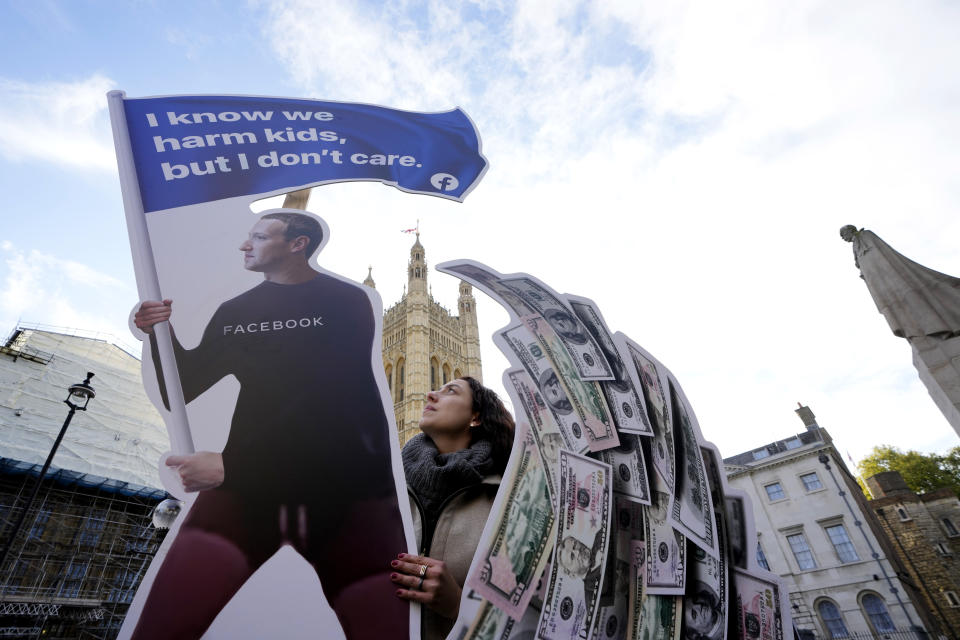 Senior campaigner from SumOfUs Flora Rebello Arduini adjusts an installation outside parliament in Westminster in London, Monday, Oct. 25, 2021. A 4-metre-high installation depicting Mark Zuckerberg surfing on a wave of cash was constructed outside parliament, as Facebook whistleblower Frances Haugen is due to testify to MPs on how the company puts profits ahead of public safety. The action comes after SumOfUs research revealed Instagram is still awash with posts promoting eating disorders, unproven diet supplements and skin-whitening products. (AP Photo/Kirsty Wigglesworth)