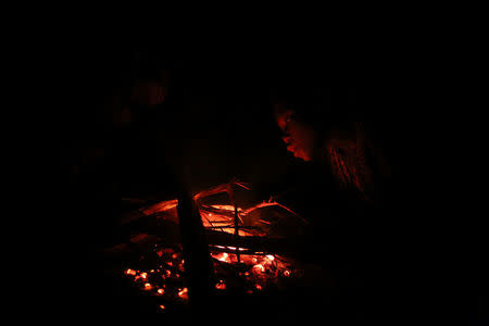 A child tries to re-light a fire at Kagorwa Pygmy camp on Idjwi island in the Democratic Republic of Congo, November 23, 2016. REUTERS/Therese Di Campo