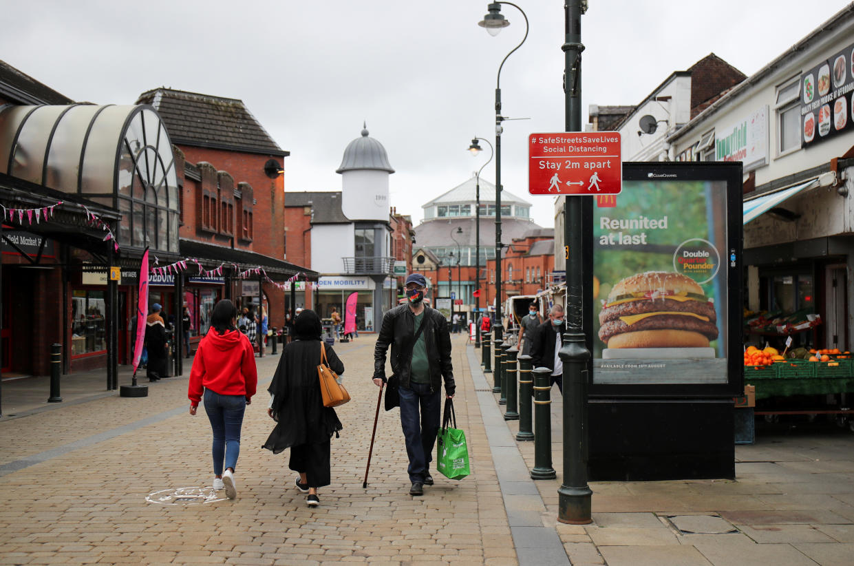 People walk past a social distancing sign, amid the outbreak of the coronavirus disease (COVID-19), in Oldham, Britain, August 19, 2020. REUTERS/Molly Darlington