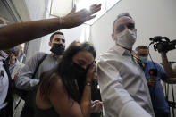 Gali Peleg, center, maternal aunt of Eitan Biran, who survived a cable car crash in Italy that killed his immediate family, leaves court in Tel Aviv on Thursday, Sept. 23, 2021 after a hearing in the alleged kidnapping of her nephew. The boy's parents and younger sibling were among 14 killed in May when a cable car slammed into a mountainside in northern Italy. He is now the focus of a custody battle between his maternal grandparents in Israel and his paternal relatives in Italy. (AP Photo/Sebastian Scheiner)