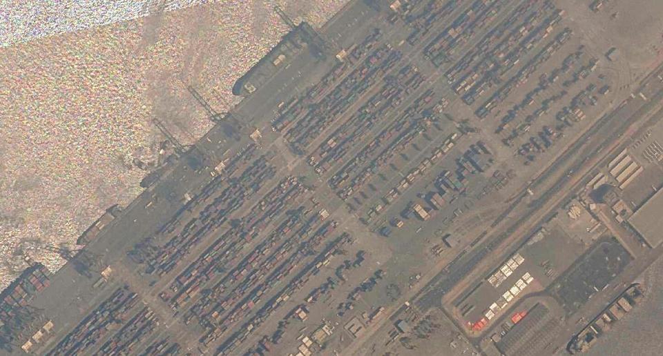 In this satellite photo shot by Planet Labs Inc., the Jebel Ali Port is seen early Thursday, July 8, 2021, in Dubai, United Arab Emirates. A fiery explosion erupted on a container ship anchored in Dubai at one of the world's largest ports late Wednesday, July 7 authorities said, sending tremors across the commercial hub of the United Arab Emirates. Two ships, upper left under cranes, are seen in the photo spraying water on the stricken vessel. (Planet Labs Inc. via AP)