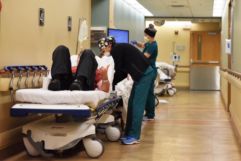 Nurses assist patients in beds in a hallway at Sparrow Hospital in Lansing.