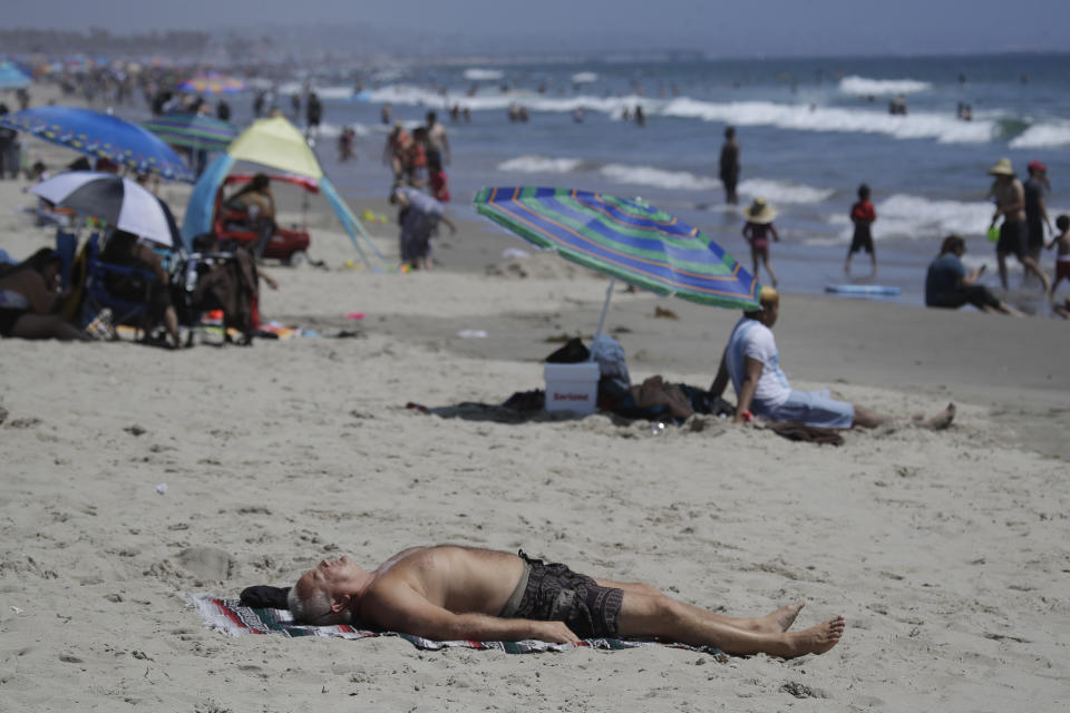 FILE - In this Sunday, July 12, 2020, file photo, a man lies on the beach amid the coronavirus pandemic in Santa Monica, Calif. The torrid coronavirus summer across the Sun Belt is easing after two disastrous months that brought more than 35,000 deaths. (AP Photo/Marcio Jose Sanchez, File)