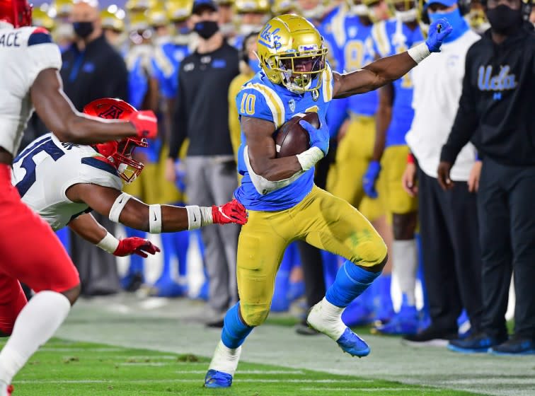 PASADENA, CA - NOVEMBER 28: Running back Demetric Felton #10 of the UCLA Bruins is just out of the reach of defensive back McKenzie Barnes #15 of the Arizona Wildcatsas he gains a first down in the first half of the game at the Rose Bowl on November 28, 2020 in Pasadena, California. (Photo by Jayne Kamin-Oncea/Getty Images)