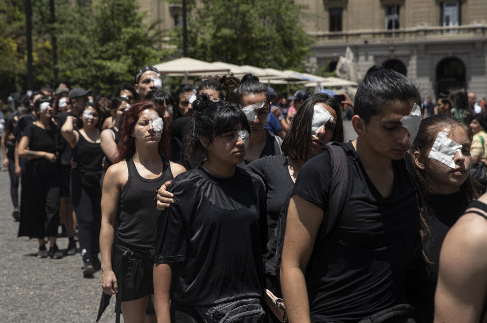 Anti-government demonstrators, wearing eye patches, perform in front of the Supreme Court in Santiago, Chile, Monday, Nov. 18, 2019. According to the Medical College of Chile at least 230 people have lost sight after being shot in an eye in the last month while participating in the demonstrations over inequality and better social services. (AP Photo/Esteban Felix)