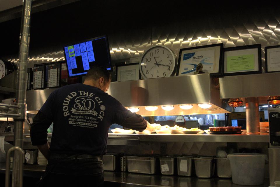 Kellum Dietz grabs dishes from the hot pass which he will later serve to the tables in his section at Round the Clock Diner.