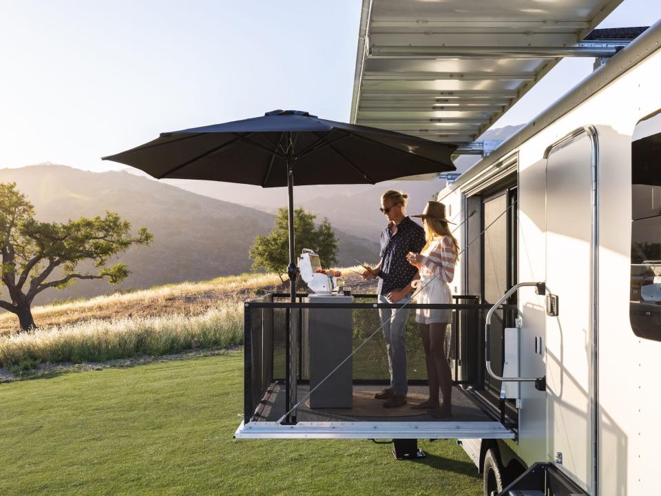 two people standing on the balcony of the 2022 Living Vehicle trailer