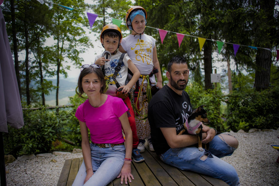 Carmela Forino and Stefano Tempestilli pose with their children Andrea, second from left, and Sofia, third from left, in a park in Civitella del Tronto, near Teramo in central Italy, Sunday, June 4, 2023. "I practice where I want. Every morning I pray on my own," Forino said. "One has to believe in something, right? You do what you feel in your heart. You can't require me to go to Mass on Sundays." (AP Photo/Domenico Stinellis)