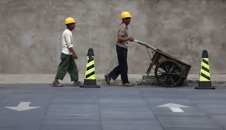 A migrant worker pushes a wheelbarrow on a construction site in central Beijing August 5, 2009. REUTERS/David Gray/Files